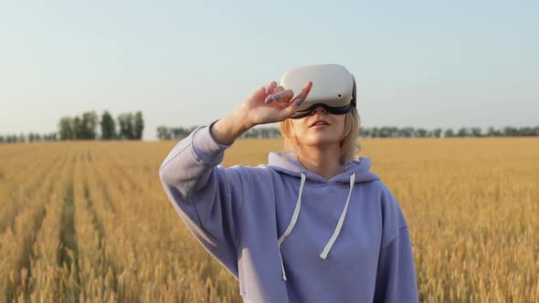 Woman Using Glasses or VR Headset Outdoors Among a Wheat Field