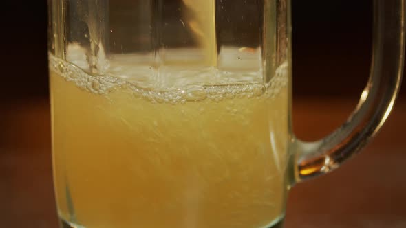 Beer pouring into a mug, at bar counter panning upwards macro shot.