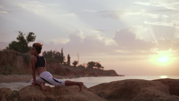Young Dark Skinned African American Girl Standing in Yoga Asana on Rocks By Sea alt