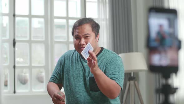 Asian Man Blogger Shoots Video Content For Social Networks By Smartphone, Magician With Playing Card alt