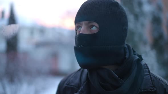 Closeup Thoughtful Thief in Balaclava Looking Inside House Through Window Glass Holding Hand at alt
