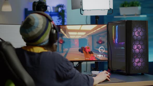 Back Shot of Pro Streamer with Headphone Playing FPS Videogame alt
