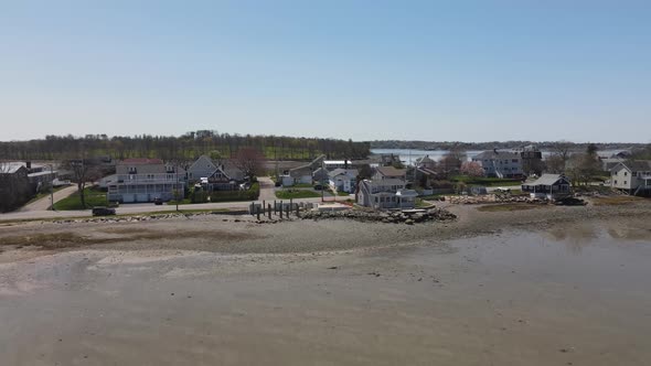 Drone retreat from the shoreline revealing a neighborhood in Hull; a partially built home; and a mud alt