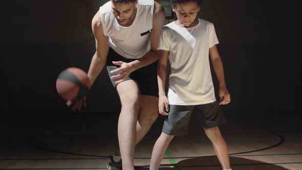 Basketball Player Teaching Son How to Dribble Ball alt
