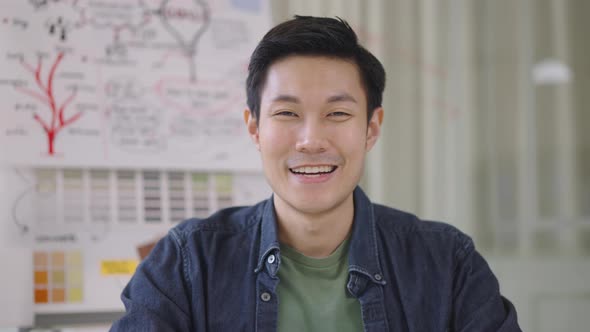 Close up portrait young Asian man smiling to camera in office