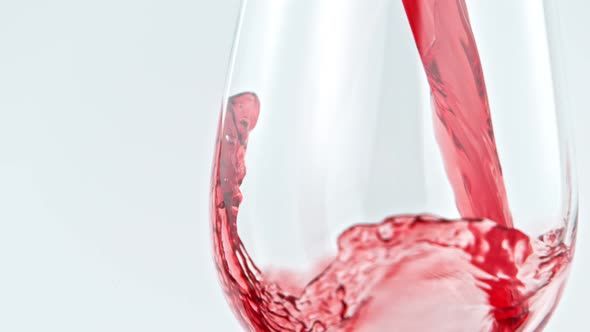 Pouring Red Wine in Super Slow Motion on White Background. alt