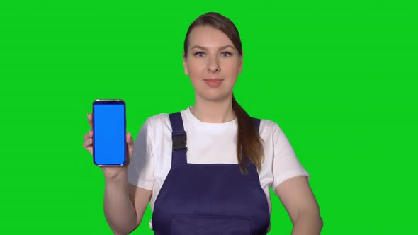 Woman Builder in Blue Overalls Hold Mobile Phone with Green Screen