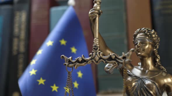 Statue of Lady Justice with Bookshelf with Books and EU Flag Background alt