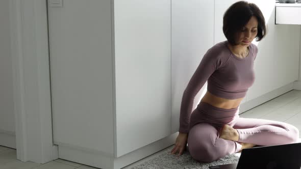 Pretty fitness young woman in violet sportswear practicing yoga exercise in lotus pose