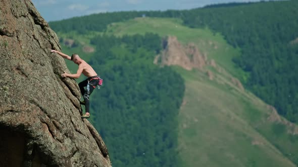 Slow Motion of a Young Strong Man Climbing Over Rocky Ledges to a High Peak