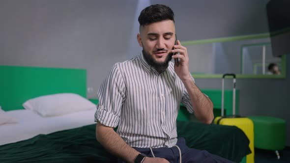 Young Bearded Confident Man Talking on the Phone After Arrival in Hotel alt