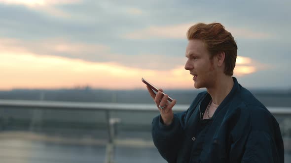 Young Guy Recording Audio Message on Smartphone alt