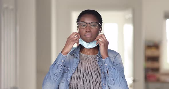 Pretty woman putting on protective face mask alt