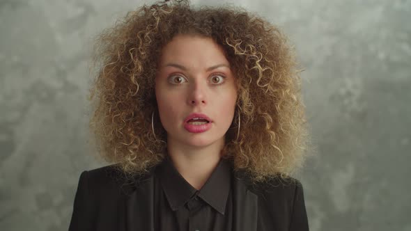 Shocked Pretty Woman with Curly Hair Looking with Astonished Expression alt