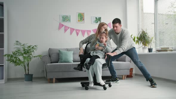 Family Relationships a Loving Father Has Fun Rolling His Wife and a Female Child on a Chair While alt