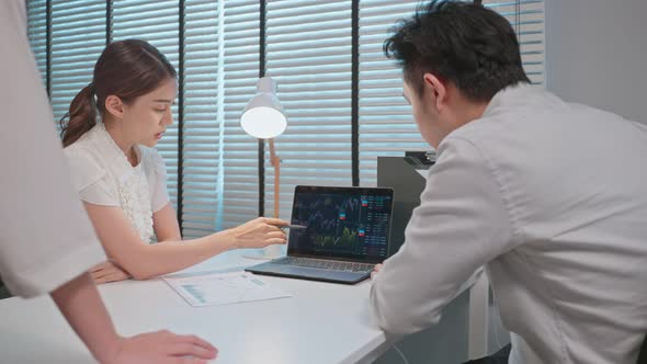 Asian broker trader advise about investment stock market and graph in office. alt