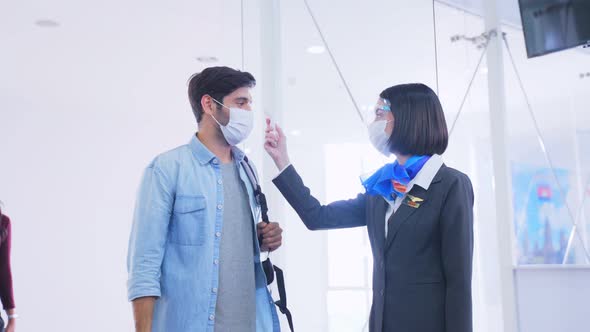 Caucasian female airline staff measuring body temperature of passenger before get to the airport. alt