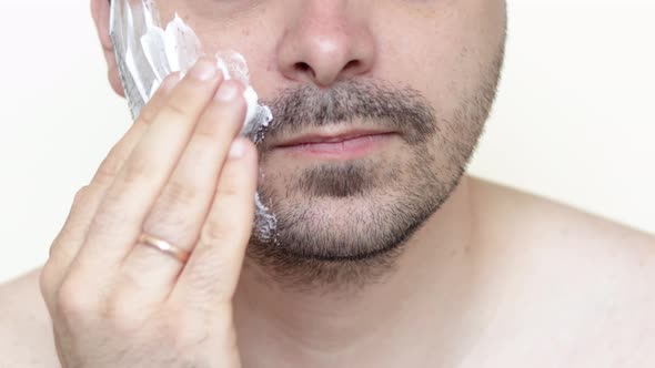 bearded man is applying shaving foam on face. skincare cosmetology concept.morning routine.bottom alt
