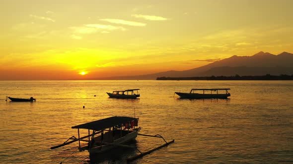 Fishing boat floating on golden lagoon water under a bright sky at sunset in Gili Islands, Indonesia alt