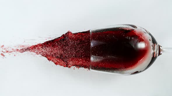 Super Slow Motion Top Shot of Falling Glass with Red Wine on White Cloth at 1000Fps alt