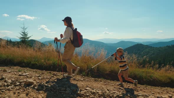 Woman and Child with Trekking Poles Hike Together Along a Rocky Path alt