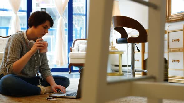 Woman using mobile phone in living room alt