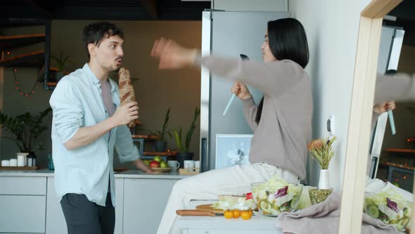 Young Man and Woman Singing Dancing Having Fun in Kitchen in Apartment alt