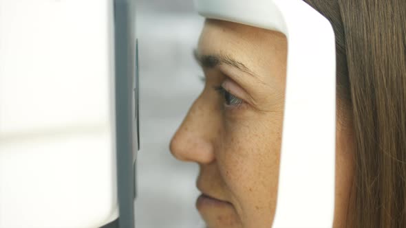 Close-up Portrait of Woman During Test of Refractometer Machine.
