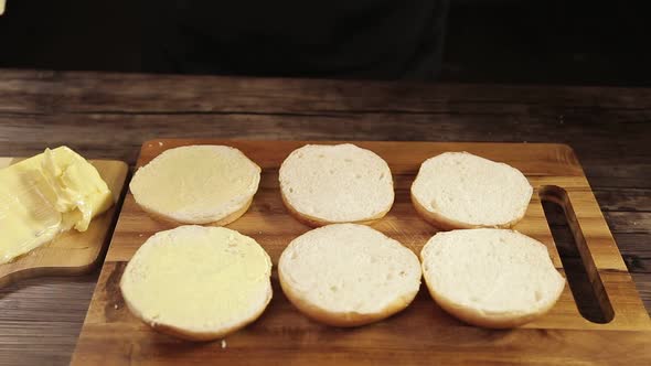 Chef Putting Butter On Six Round Burger Buns