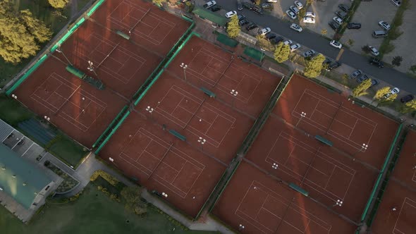 Aerial high angle view revealing tennis courts between a golf course and a parking lot on a sport cl alt