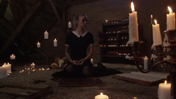 Young Woman Kneeling In Attic Of Lit Candles alt