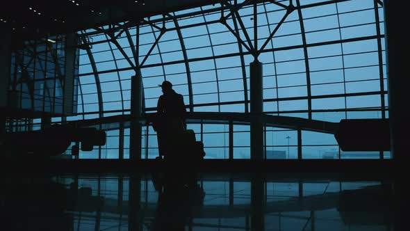 Silhouette of a Man at the Airport with Baggage. People Talking on the Phone at the Airport