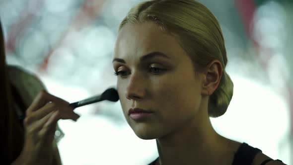 Makeup artist applying blush on womens face