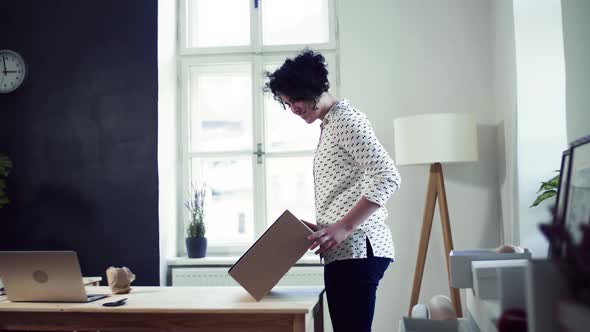 Young online shop owner packing box with items ordered by client alt