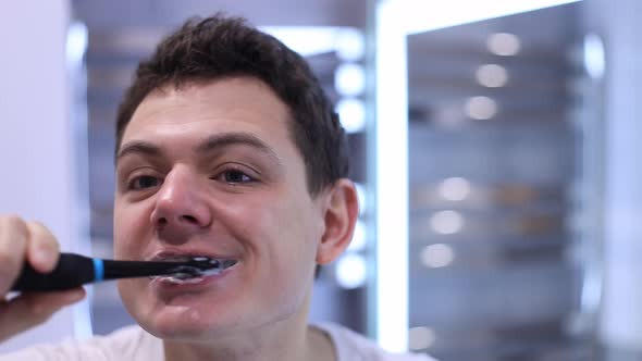 Man Cleaning His Teeth with an Electric Toothbrush alt