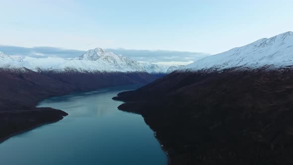 Drone shoot the shores of a frozen lake between snow-capped mountains in Eklutna Lake, Alaska, USA alt