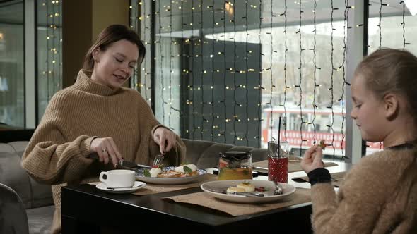 Mother and Daughter Have a Delicious Meal in a Cafe alt