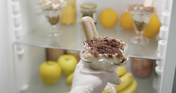 4K - Chef hand puts Tiramisu dessert in the fridge alt