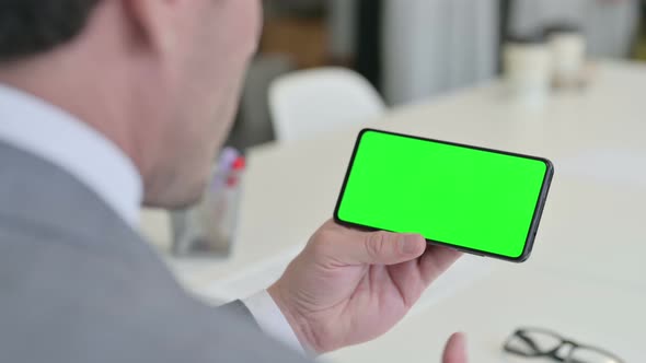 Businessman Looking at Smartphone with Green Chroma Key Screen alt