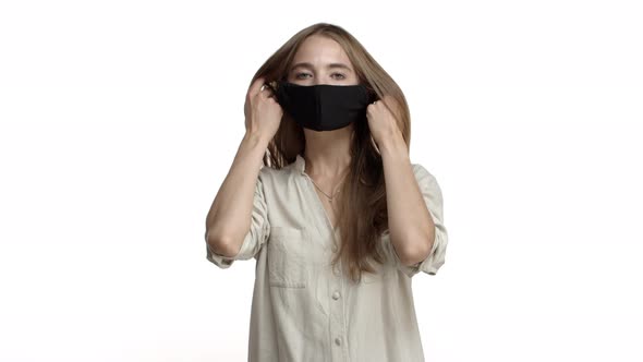 Video of Attractive Adult Woman with Long Fair Hair Wearing Casual Blouse Takingoff Black Face Mask alt