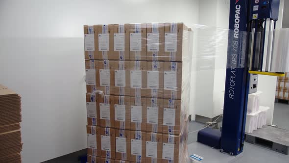 The Automated Machinery is Rotating and Packing in Plastic Wrap a Batch of Boxes Filled with alt
