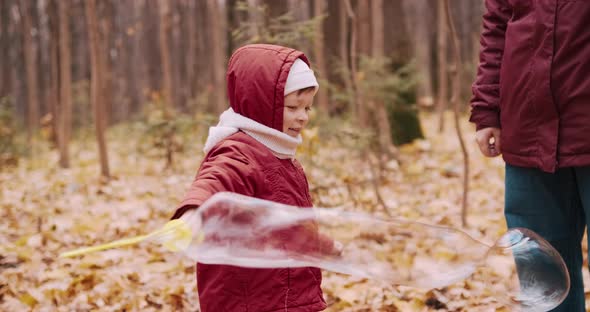 Little Girl Blowing Soap Bubbles in an Autumn Park