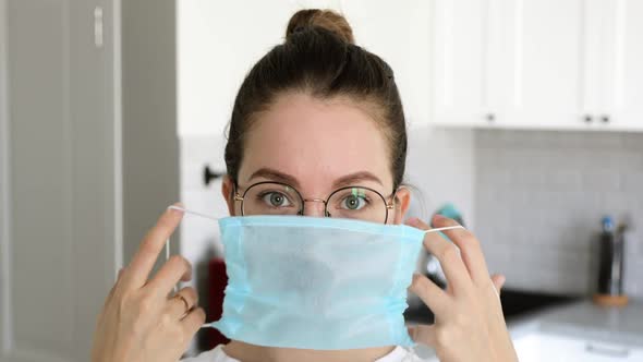 Portrait of Woman Putting on Medical Mask in Coronavirus Pandemic at Home.