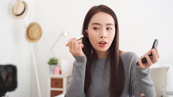 Young beautiful Asian woman professional beauty vlogger doing cosmetic makeup tutorial online