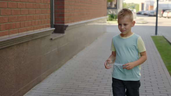 Little Boy is Holding the Glass Bottle and Puts It to the Correct Bin for Glass alt