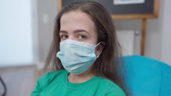 Brunette Little Person in Coronavirus Face Mask Looking at Camera with Serious Facial Expression alt