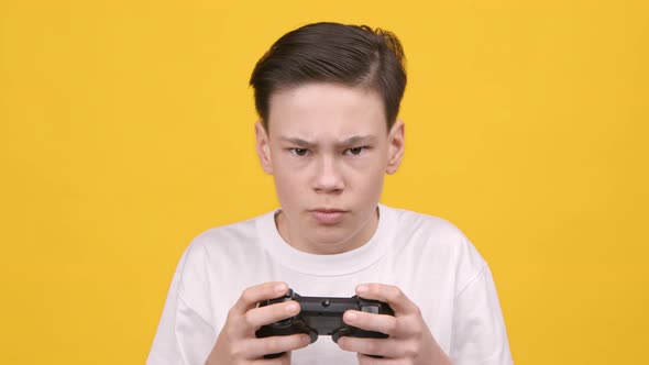 Teenager Boy Playing Videogame Holding Gamepad Controller Over Yellow Background alt