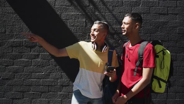 Two happy mixed race friends using smartphone in the street alt