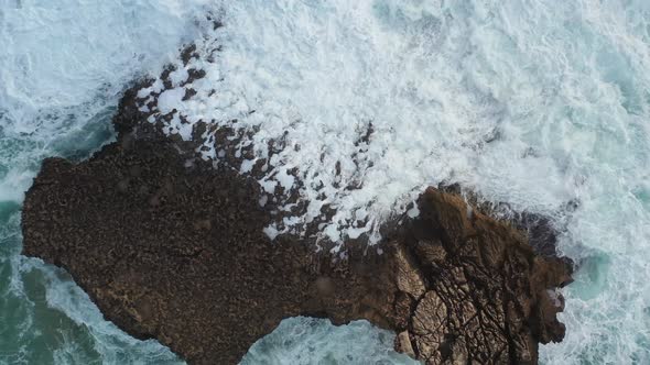 Large Ocean rock battered by waves in Praia Do Tonel, near Cape Sagres Portugal, Aerial rising shot alt