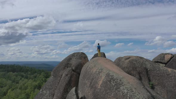 A Lone Man Stands on the Top of a Mountain and Enjoys a Beautiful View of the Forest alt